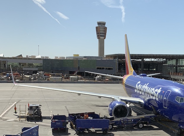 Southwest Airlines plane parked at a gate at Phoenix Sky Harbor Airport, with the control tower visible in the background